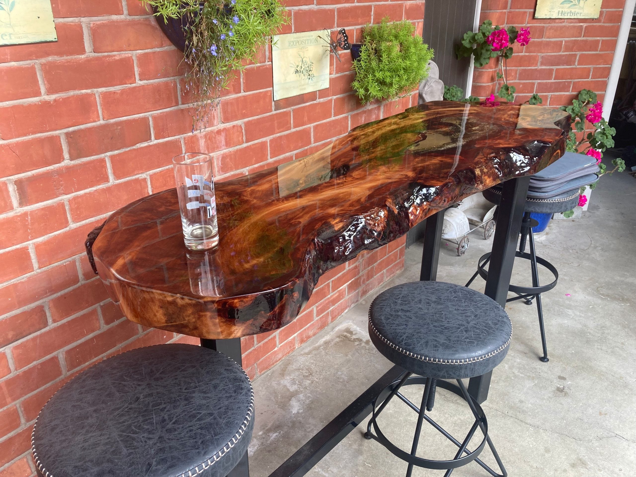 Swamp kauri and resin bar leaner with bar stools against a brick wall
