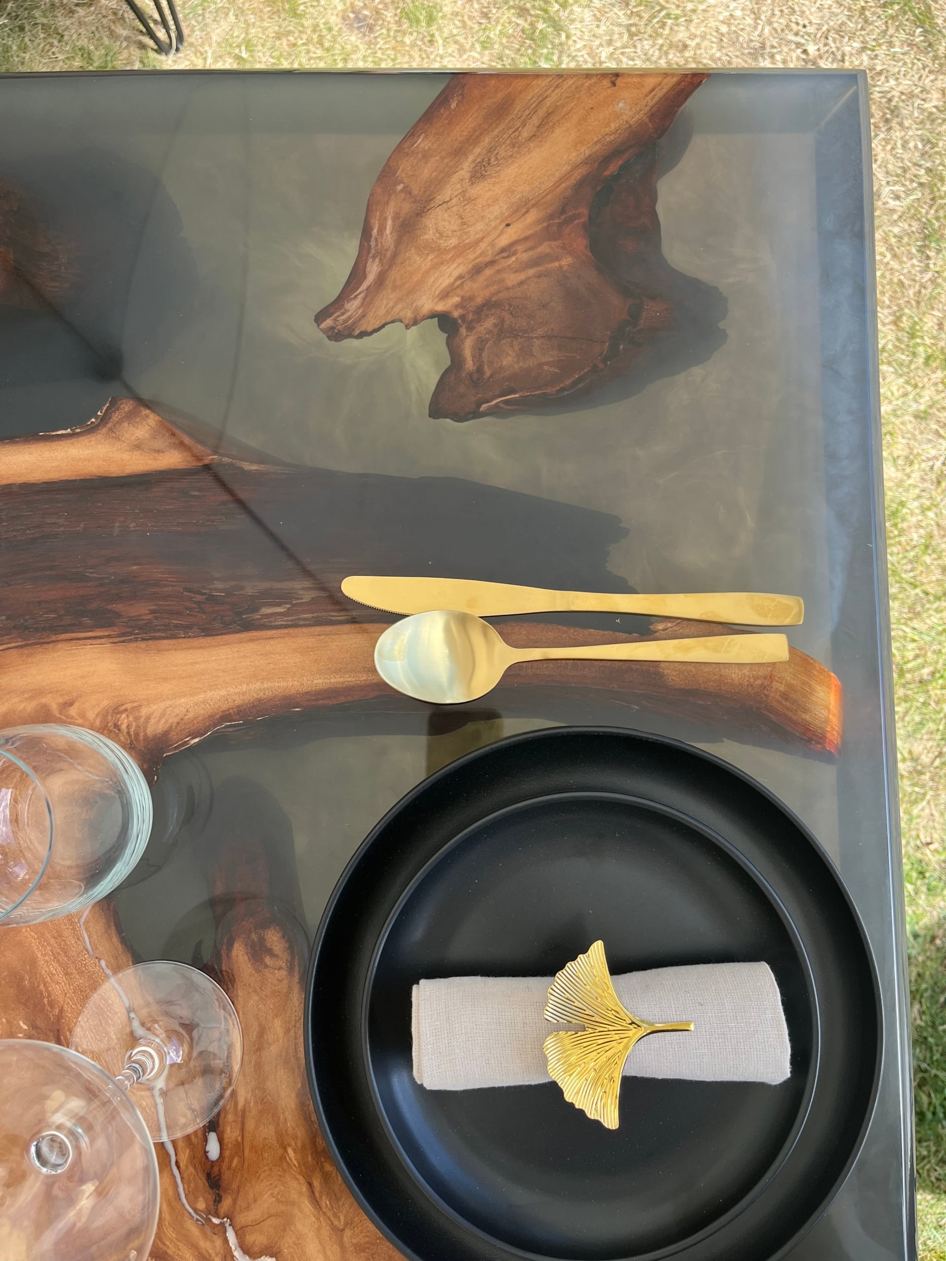 Swamp kauri and grey resin dining table set with black plates and gold cutlery